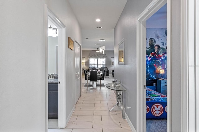 hall with visible vents, baseboards, and an inviting chandelier
