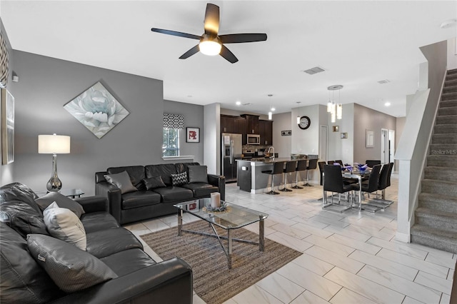 living room featuring recessed lighting, visible vents, a ceiling fan, and stairs
