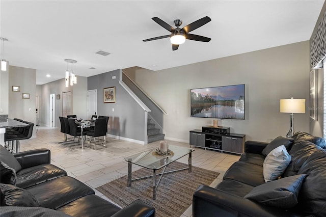 living room featuring visible vents, baseboards, stairs, and ceiling fan
