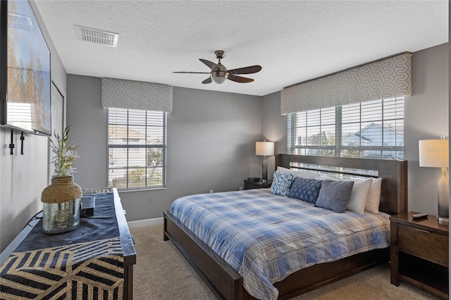 bedroom featuring visible vents, a ceiling fan, baseboards, a textured ceiling, and carpet flooring