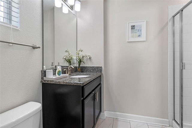 bathroom with baseboards, vanity, a shower stall, and toilet