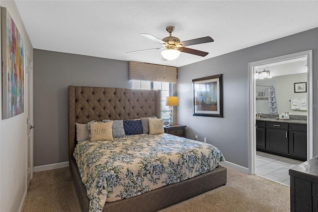 bedroom featuring light carpet, a ceiling fan, baseboards, and ensuite bathroom