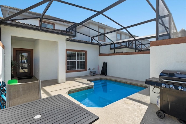 outdoor pool featuring glass enclosure, grilling area, and a patio area