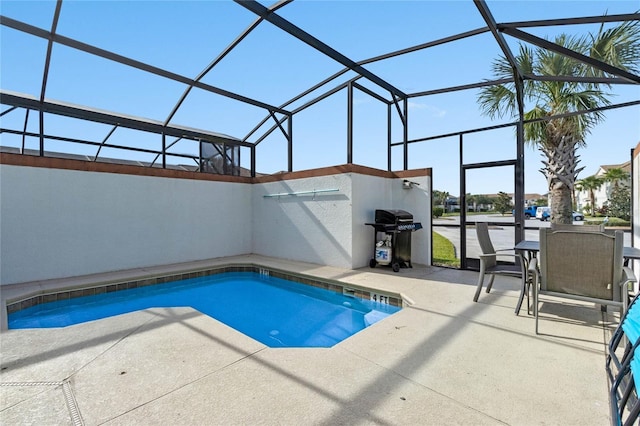 outdoor pool with a patio area, glass enclosure, and a grill
