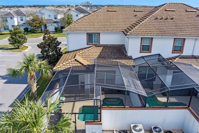 rear view of house featuring an outdoor pool, a tiled roof, glass enclosure, and a patio area