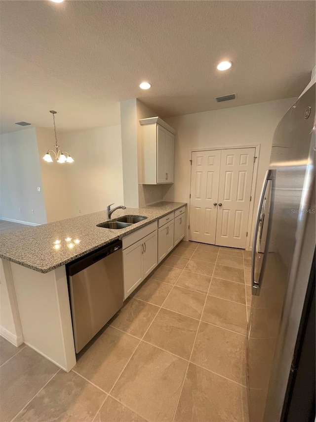 kitchen featuring stainless steel appliances, white cabinetry, a notable chandelier, and sink