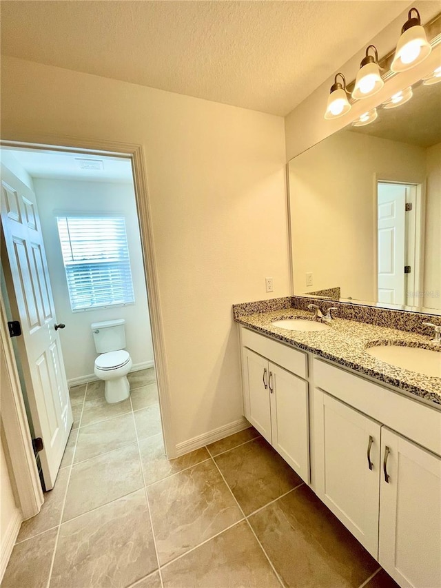 bathroom with vanity, a textured ceiling, toilet, and tile patterned flooring