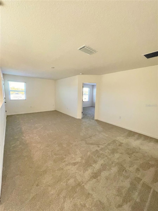 carpeted spare room with a textured ceiling