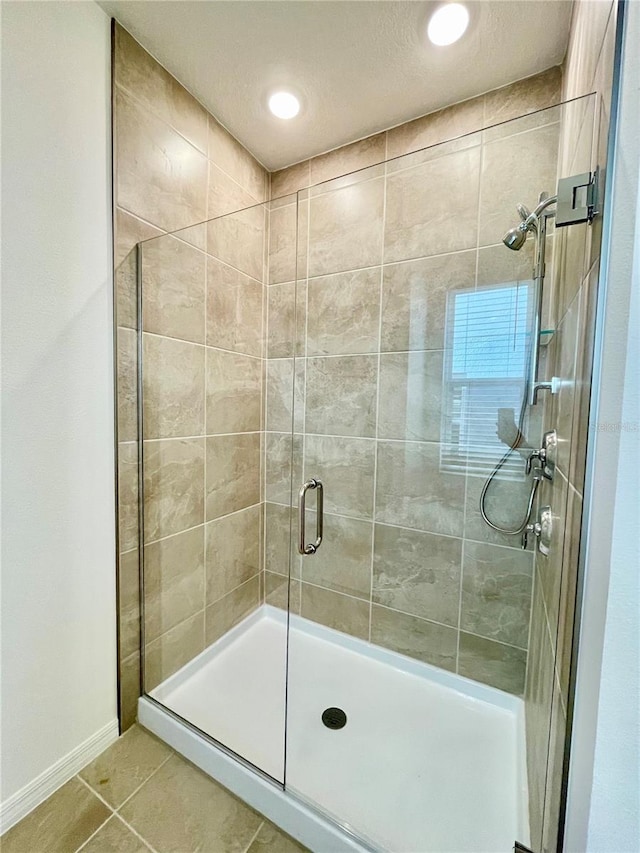 bathroom featuring tile patterned floors, a shower with shower door, and a textured ceiling