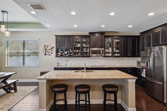 kitchen featuring dark hardwood / wood-style flooring, sink, stainless steel appliances, and a kitchen island with sink