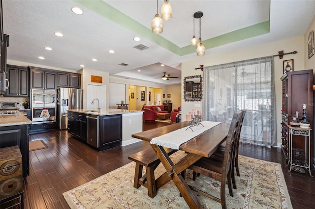 dining room featuring dark hardwood / wood-style flooring, ceiling fan, a raised ceiling, and sink