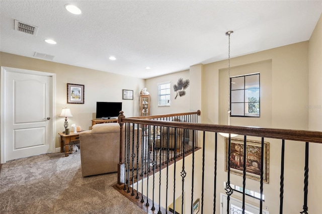 hall with a textured ceiling and carpet floors