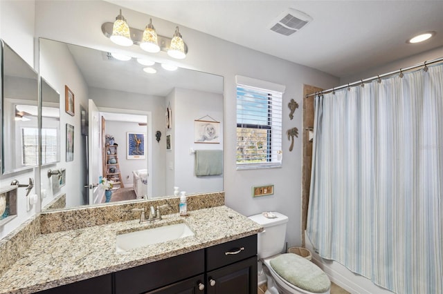 full bathroom featuring shower / tub combo, vanity, toilet, and a healthy amount of sunlight