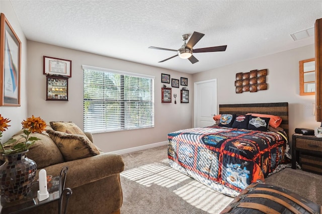 carpeted bedroom featuring ceiling fan and a textured ceiling