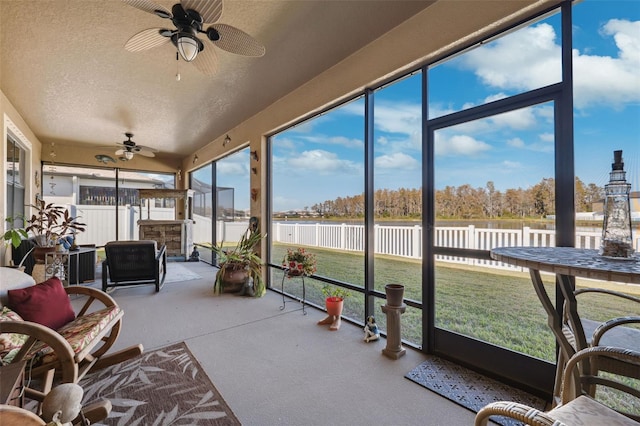 sunroom / solarium featuring ceiling fan and a water view