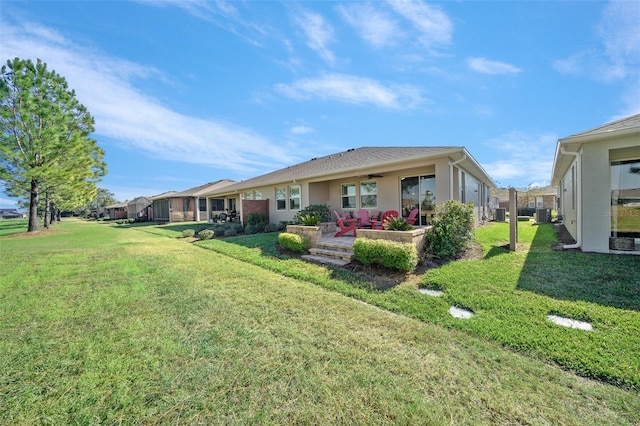 rear view of property featuring a lawn and ceiling fan