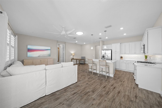 living room with wood-type flooring, ceiling fan, and sink