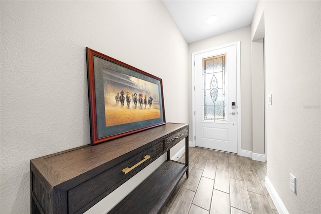 foyer with vaulted ceiling and light hardwood / wood-style flooring