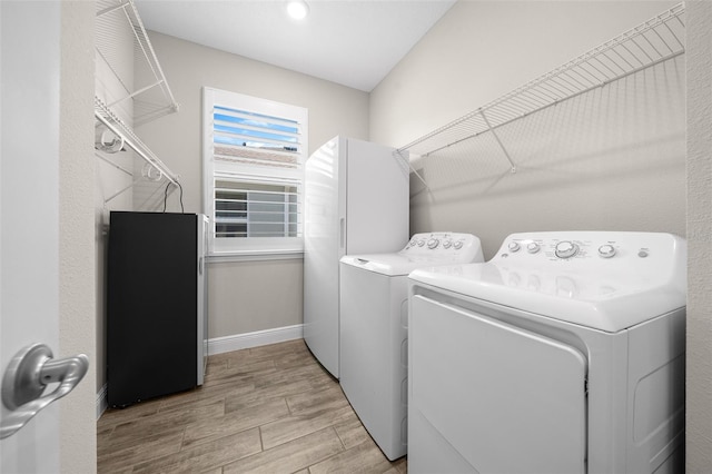 clothes washing area featuring washing machine and dryer and light hardwood / wood-style flooring