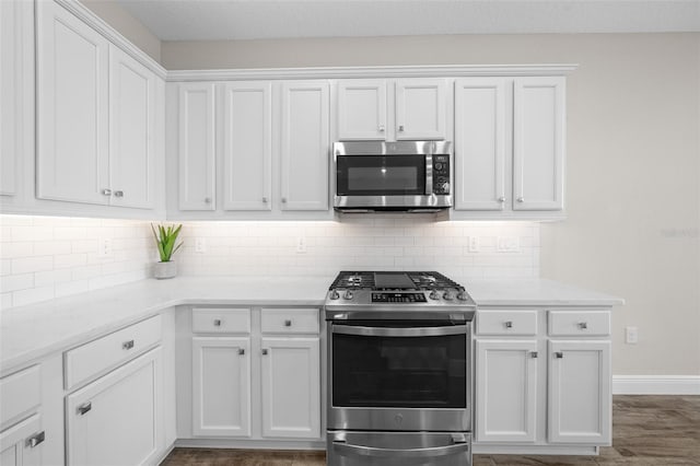 kitchen with white cabinetry, light stone countertops, tasteful backsplash, dark hardwood / wood-style floors, and appliances with stainless steel finishes