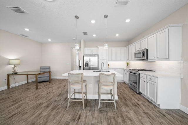 kitchen with white cabinets, sink, dark hardwood / wood-style floors, appliances with stainless steel finishes, and decorative light fixtures