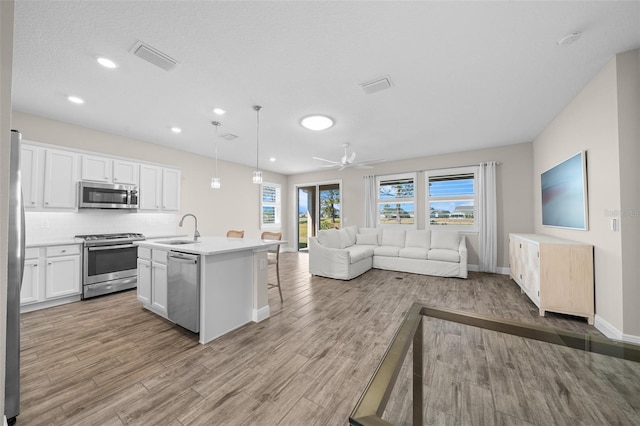 kitchen featuring pendant lighting, white cabinets, sink, an island with sink, and stainless steel appliances