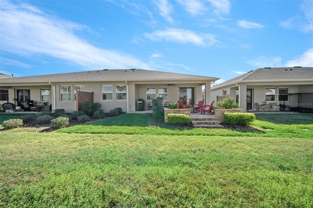 back of property with a lawn, ceiling fan, and a patio