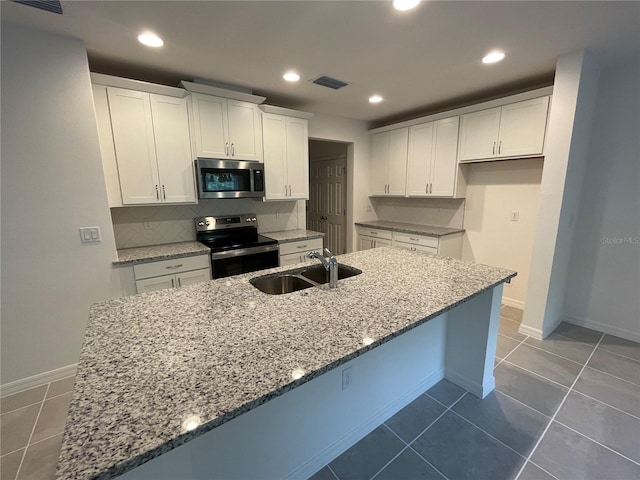 kitchen with white cabinets, sink, light stone countertops, and stainless steel appliances