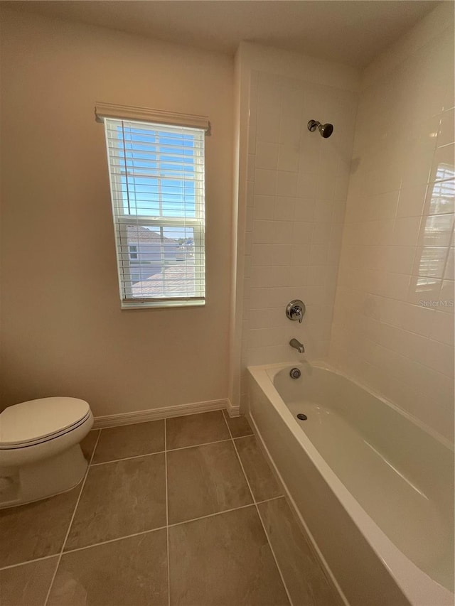 bathroom with tile patterned floors, tiled shower / bath combo, and toilet