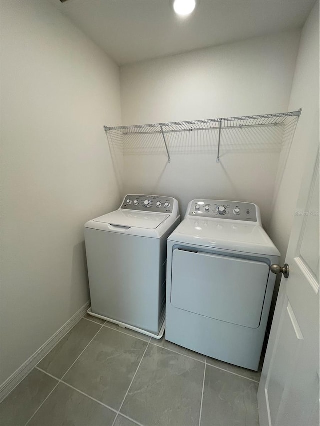 laundry area with dark tile patterned flooring and washer and clothes dryer