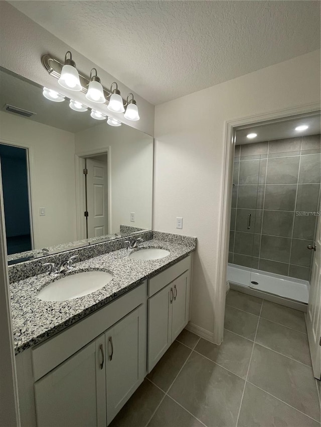 bathroom with tile patterned flooring, a textured ceiling, vanity, and a shower with shower door