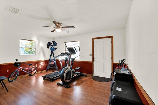 workout area featuring a textured ceiling, hardwood / wood-style flooring, and ceiling fan