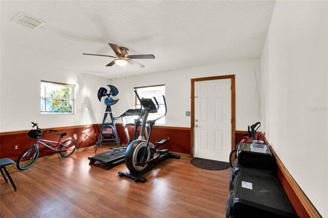 workout area featuring a textured ceiling, hardwood / wood-style flooring, and ceiling fan