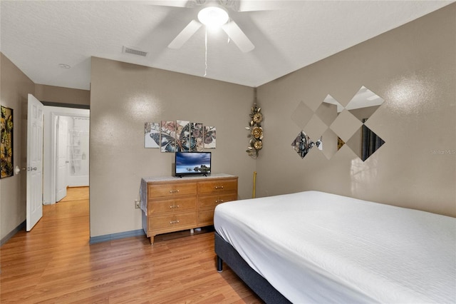 bedroom featuring ceiling fan, light hardwood / wood-style floors, and a textured ceiling