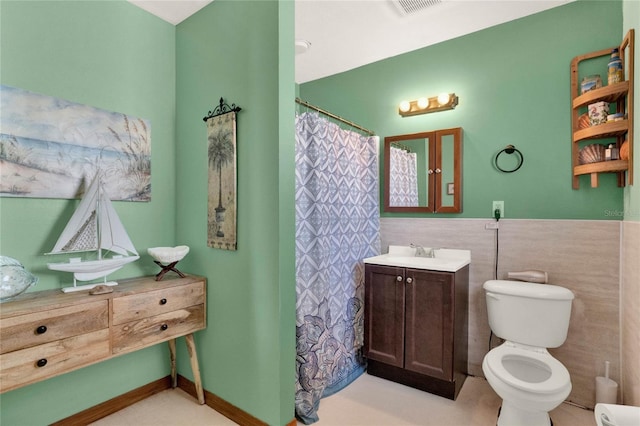 bathroom featuring a shower with shower curtain, vanity, toilet, and tile walls