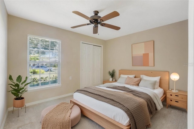 bedroom with ceiling fan, a closet, and light colored carpet