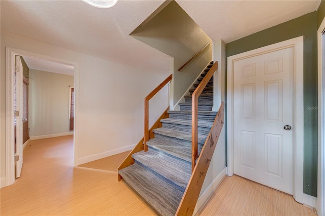 stairs with hardwood / wood-style floors and a textured ceiling