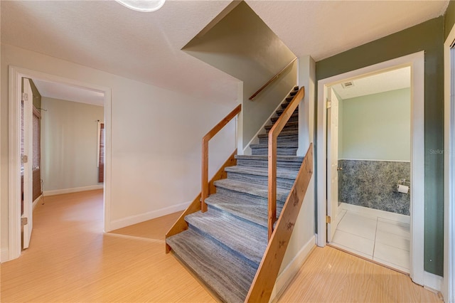 staircase with a textured ceiling and hardwood / wood-style flooring