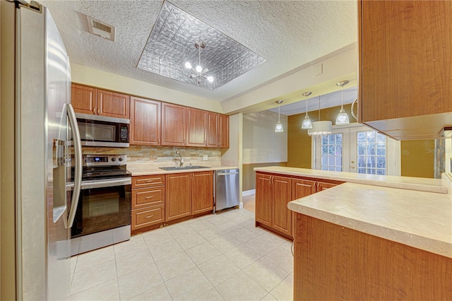 kitchen featuring sink, decorative backsplash, light tile patterned floors, appliances with stainless steel finishes, and decorative light fixtures