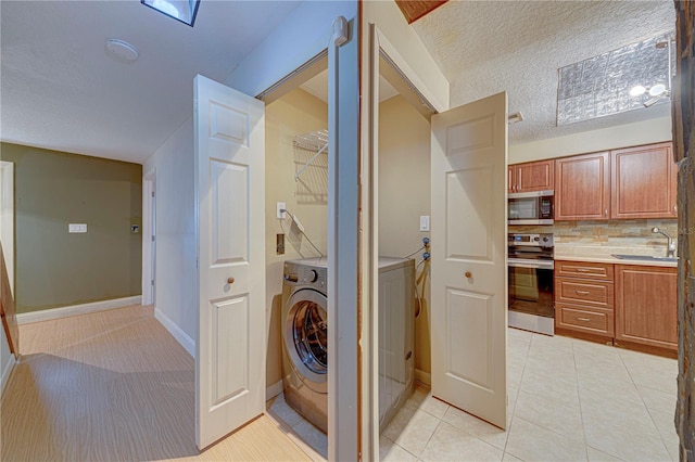 laundry room with washer / dryer, a textured ceiling, light tile patterned floors, and sink