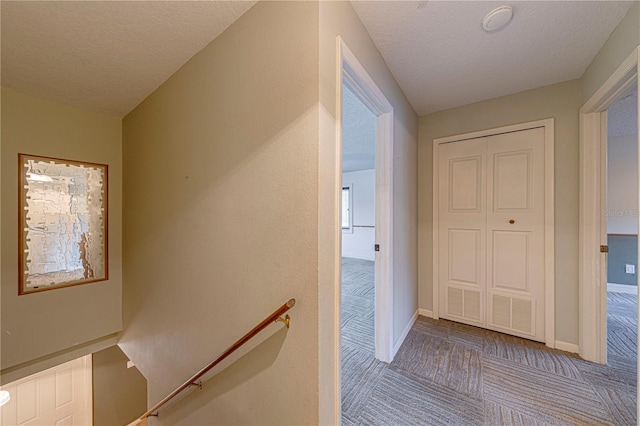 corridor with a textured ceiling and light colored carpet