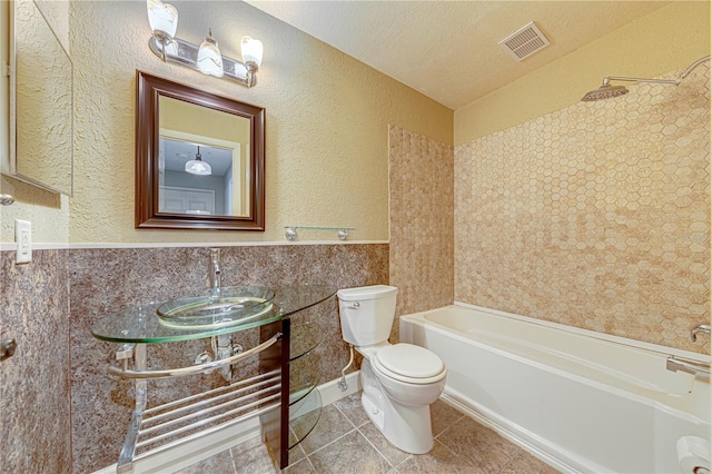 full bathroom with tile patterned floors, tub / shower combination, a textured ceiling, sink, and toilet