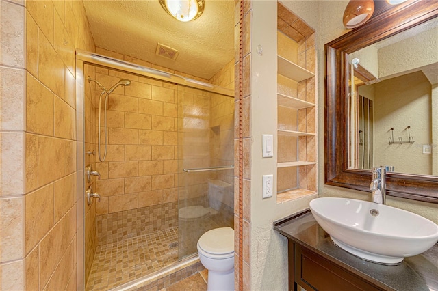 bathroom featuring tile patterned floors, a textured ceiling, toilet, vanity, and a shower with shower door