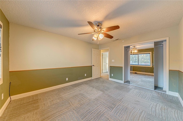 unfurnished bedroom with carpet flooring, ceiling fan, a textured ceiling, and a closet