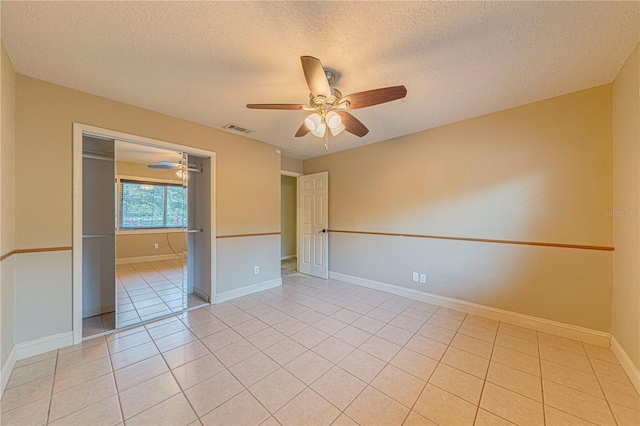 tiled spare room featuring a textured ceiling and ceiling fan