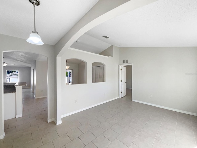 tiled empty room with a textured ceiling, ceiling fan, and lofted ceiling