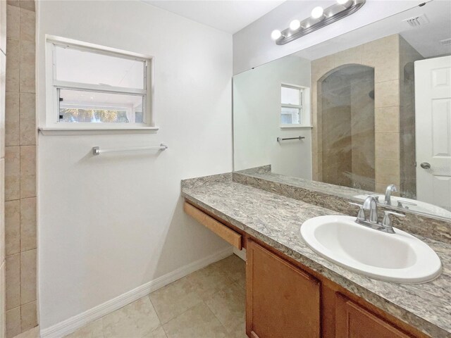 bathroom featuring tile patterned flooring, vanity, and tiled shower