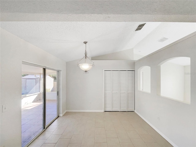 tiled empty room with lofted ceiling and a textured ceiling