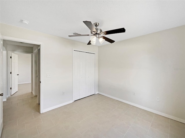 unfurnished bedroom featuring light tile patterned floors, a textured ceiling, a closet, and ceiling fan