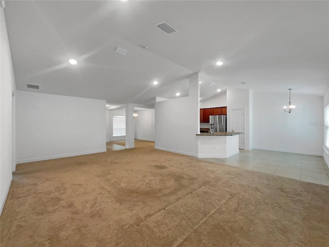 unfurnished living room with light carpet, vaulted ceiling, and a notable chandelier